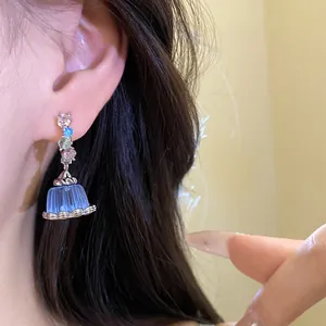 Detailed shot of elegant zircon earrings with a translucent blue resin pudding pendant