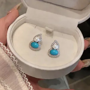 Detailed view of silver needle gourd earrings with turquoise and pearls in a gift box