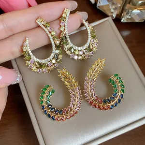 Dettaglio di eleganti orecchini a spiga di grano a forma di C con zirconi colorati.