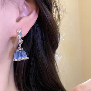 Close-up of an elegant blue resin pudding earring with colorful zircons on a model.
