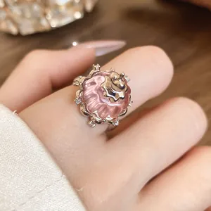 Detailed close-up of an elegant pink resin pudding ring with zircon embellishments on a finger