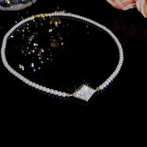 Macro detail of a 18K gold-plated pearl necklace with a sparkling zircon pendant