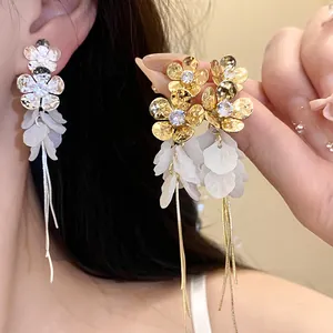 Gros plan de boucles d'oreilles à pampilles fleurs avec pétales en résine et zircons