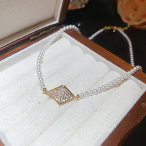 Close-up of 18K gold-plated zircon diamond pendant on a vintage pearl beaded necklace.