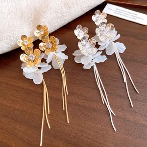Vue détaillée des boucles d'oreilles à pompons fleuris avec pétales en résine brillants.