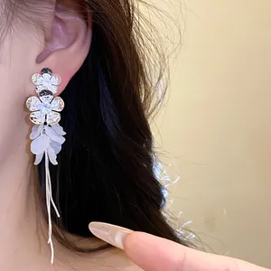 Gros plan détaillé montrant d'élégantes boucles d'oreilles fleur et pompon sur une oreille