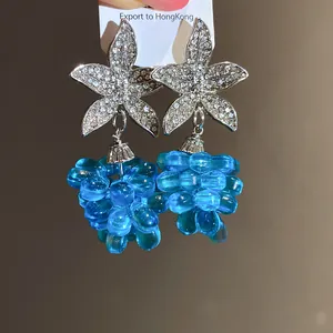 Nahaufnahme von silbernen Blumenohrringen mit transparenten blauen Perlenanhängern