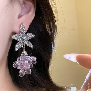 Nahaufnahme von silbernen Blumenohrringen mit Kristallen und rosa halbtransparenten Perlen