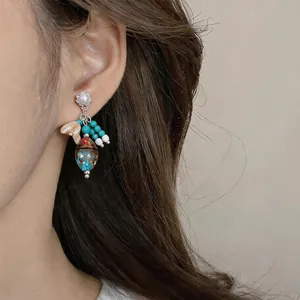 Vista detallada de pendientes de perlas vintage con cuentas turquesas en una modelo