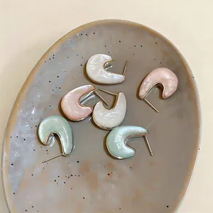 Vista dettagliata di orecchini geometrici colorati in resina disposti su un piatto ceramico