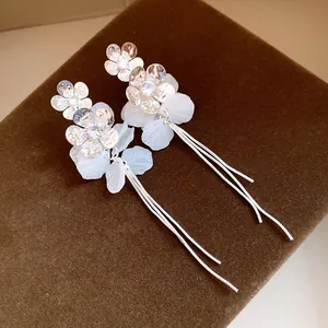 Gros plan détaillé de boucles d'oreilles fleurs argentées avec pétales en résine et pompons