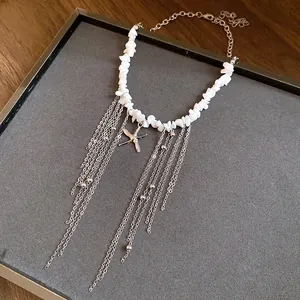 Close-up detail of a white beaded stone necklace featuring a silver starfish and long chain tassels