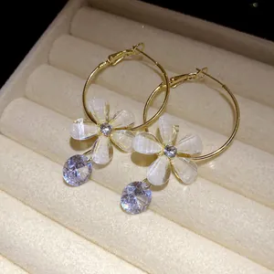 Macro view of gold hoop earrings with resin flowers and zircon charms