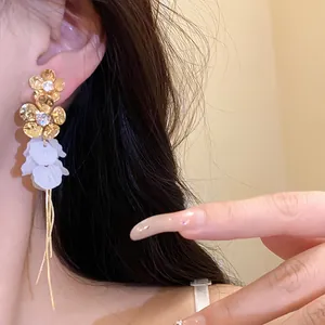 Gros plan de boucles d'oreilles à fleurs avec pétales en résine blanche et détails dorés