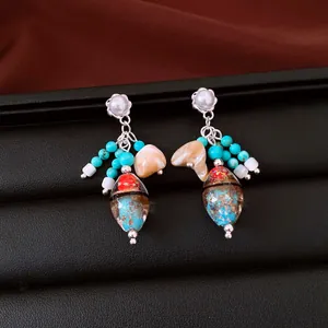 Primer plano de pendientes vintage de plata con perlas, turquesas y cuentas de cristal
