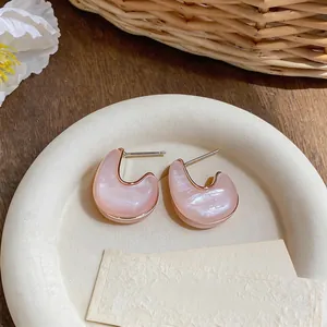 Primo piano di orecchini geometrici in resina rosa con perni in argento su piatto
