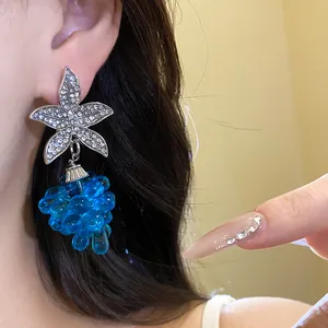 Nahaufnahme von silbernen Strass-Blumenohrringen mit blauen Perlen-Traubenanhängern