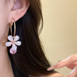 Detail of resin flower hoop earring with pink zircon pendant for a sweet vintage look