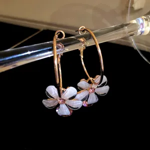 Close-up of elegant resin flower hoop earrings with zircon center on a black background.