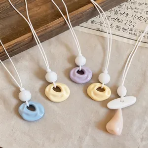 Vibrant dopamine resin pendant necklace with unique wrinkled circular design and white cord