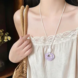 Minimalist lavender wrinkled resin pendant necklace with white cord shown on model.
