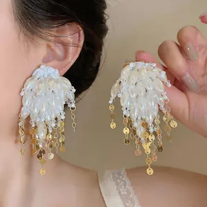Close-up view of elegant white pearl tassel earrings with dangling gold sequins for women