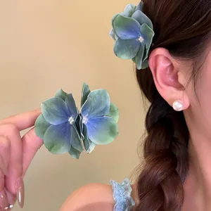Detailed view of blue and green hydrangea flower hair clips worn on a braided hairstyle.