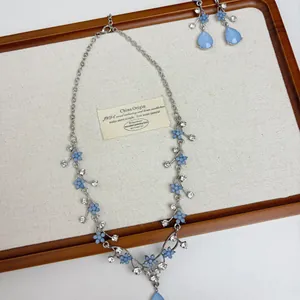 Close-up detail of blue floral necklace set with sparkling rhinestone water drop pendants