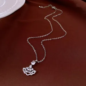 Elegant zircon fan-shaped pendant necklace with vintage silver finish on dark fabric.