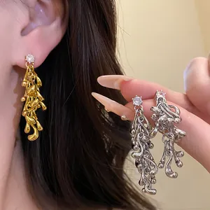 Close-up of irregular geometric tassel earrings with zircon studs in gold and silver.