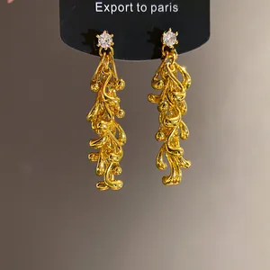 Detailed view of gold irregular geometric tassel earrings with white stone accents.