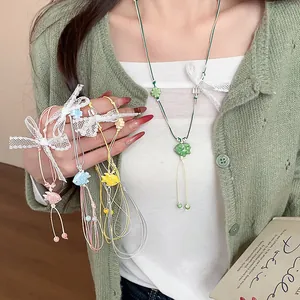 Close-up of colorful ceramic fish necklaces with lace bows worn with a green cardigan