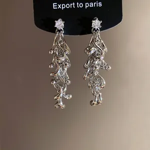 Close-up of elegant irregular silver tassel earrings with sparkling cubic zirconia.