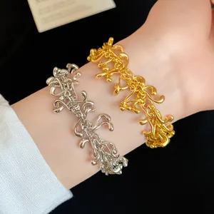 Close-up of irregular geometric tassel bracelets in gold and silver finish on wrist