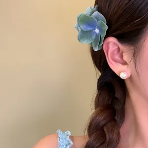 Detailed shot of a blue and green gradient flower hair clip worn by an elegant model
