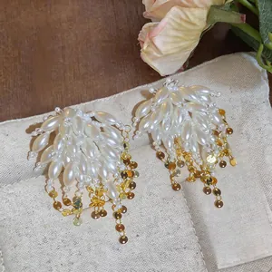 Detailed macro shot of pearl tassel earrings with golden sequins on beige pouch.
