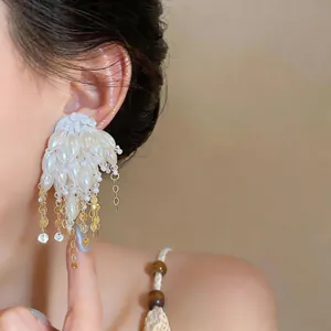 Close-up of elegant pearl tassel earrings worn on ear showing fine texture detail