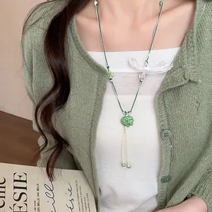 Close-up detail of the handmade green ceramic fish necklace pendant with woven cord.