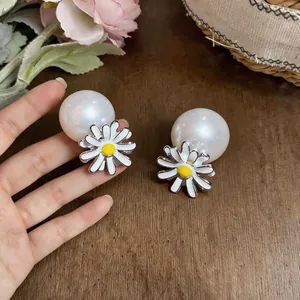 Close-up of elegant daisy flower and pearl stud earrings on a wooden background