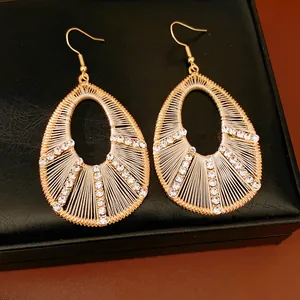 Gros plan de boucles d'oreilles dorées en forme de goutte avec tissage et strass