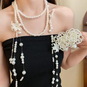 Detail view of multi-layer pearl necklace featuring intricate white shell flower charms