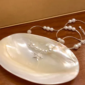 Primo piano elegante di un ciondolo a stella in zircone e perle bianche su un vassoio in madreperla