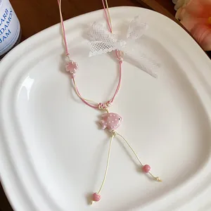 Detailed view of handmade ceramic fish pendant necklace with lace bow decoration