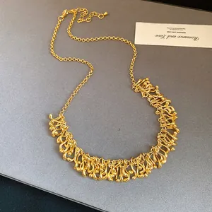 Detailed view of an irregular geometric gold liquid metal choker necklace on grey surface