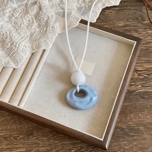 Detail showing the blue wrinkled resin pendant and white cord on a jewelry tray