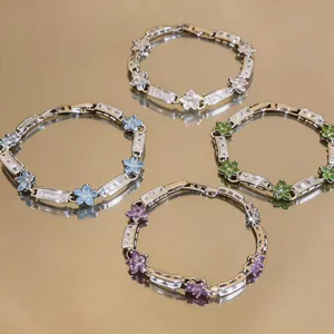 Elegant floral zircon bracelets in four colors on a reflective gold surface.