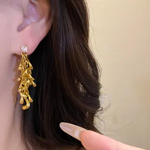 Close-up detail of vintage irregular gold tassel earrings featuring a sparkling stud