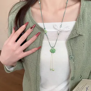 Detailed view of a handmade green ceramic fish necklace with woven leather cord