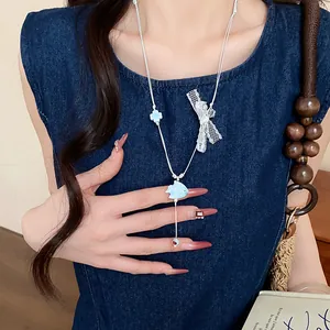 Close-up of sweet ceramic fish necklace with lace bow on a denim dress.