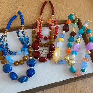 Vue détaillée de colliers en perles de résine acrylique bohème sur un plateau.